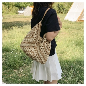 Detailed close-up of a large woven straw tote bag featuring intricate hollow geometric patterns