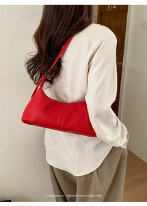 Detail of red pebbled leather hobo bag with sleek curved structure and vertical stitching