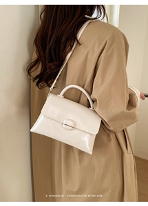 Close-up of a minimalist cream white retro square bag with a top handle and shoulder strap