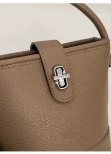 Detail of khaki lychee grain leather bucket bag featuring a silver metal twist lock clasp