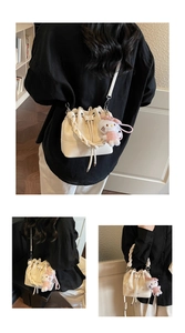 Detail of cream bucket bag with star embroidery, woven handle and plush kitten charm