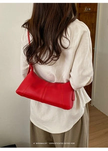 Detailed view of red pebble leather dumpling bag worn on shoulder by a model