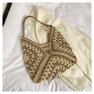 Detail of hand-woven straw tote with geometric hollow pattern and brown leather straps