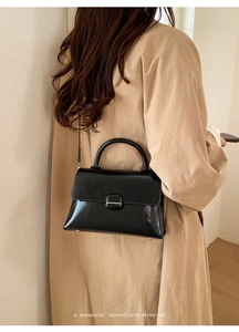 Close-up of minimalist black leather handbag with silver clasp and a retro vibe