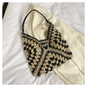 Detail view of woven checkered tote bag with black granny square pattern and leather strap
