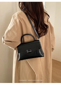 Chic black glossy handbag with minimalist metal clasp shown on a model in daily life