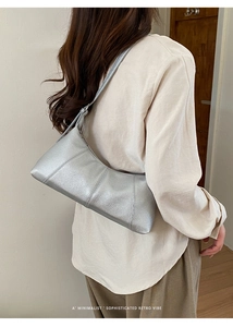 Detailed view of silver shoulder bag with lychee grain texture worn by a model
