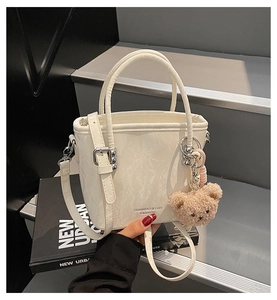 Détail du sac seau à motif marbre blanc avec boucles argentées et breloque ours