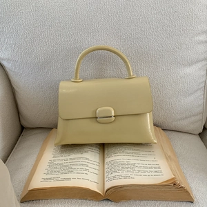 Detail of light yellow square handbag with leather texture on vintage books