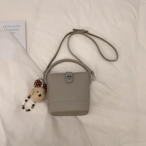 Detail of taupe bucket bag featuring pebble grain leather and cute bear charm pendant