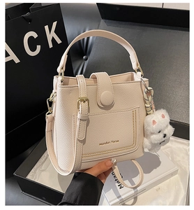Détail du sac seau en cuir grainé blanc cassé avec pendentif chien en peluche
