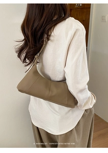 Detail view of coffee brown litchi leather bag with stitching on a model's shoulder