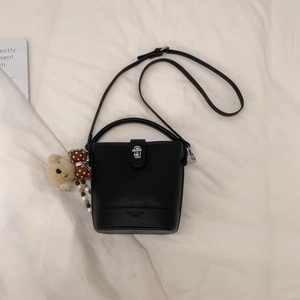Close-up of black bucket bag with silver lock, bear charm and polka dot bow detail