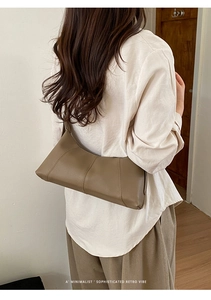 Minimalist brown pebbled leather shoulder bag with geometric stitching shown on model