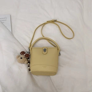 Detail view of yellow bucket bag with litchi texture and cute bear pendant charm