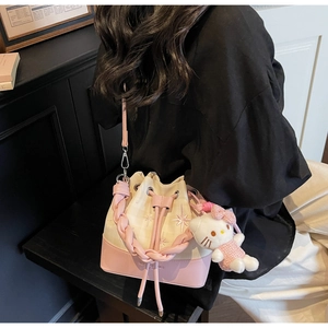 Detail of a vintage bucket bag with star embroidery, woven handle, and plush kitten charm
