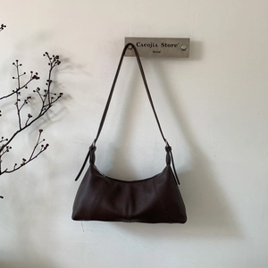 Detail of dark brown lychee textured leather baguette bag with adjustable strap