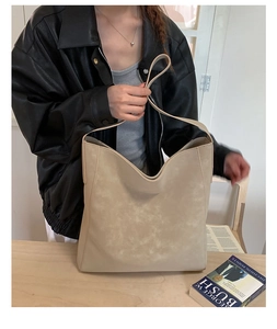 Dettaglio della grande borsa tote beige indossata da modella con giacca di pelle