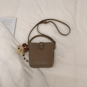 Detail of tan pebble leather bucket bag with silver twist lock and cute bear charm