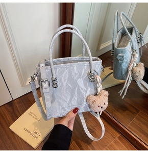 Détail du sac seau bleu clair plissé avec doubles poignées et charm d'ours mignon