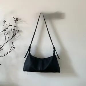 Detail of black lychee-grain leather texture on a half-moon shoulder hobo bag