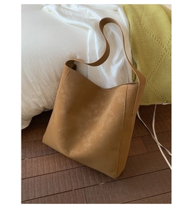 Dettaglio di una borsa tote in ecopelle marrone con tracolla larga su sfondo bianco