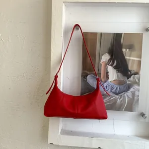 Detail view of red lychee pattern leather underarm bag with silver buckle and thin strap