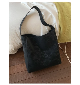 Dettaglio della borsa tote nera opaca in finta pelle scamosciata in una camera