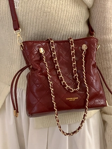 Quilted burgundy crossbody bucket bag with gold chain strap and drawstring closure