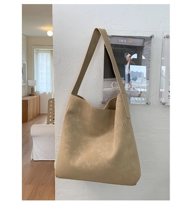 Dettaglio della borsa tote in pelle scamosciata kaki con tracolla larga in interni moderni