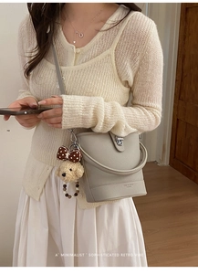 Detail of grey lychee leather bucket bag with silver lock and cute puppy charm