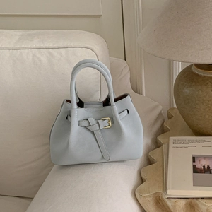 Close-up of light blue bucket bag with knotted leather strap and gold metal hardware detail