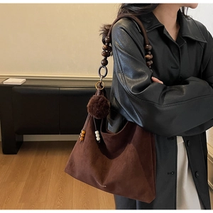 Detail of vintage brown suede hobo bag with wooden bead strap and decorative tassels