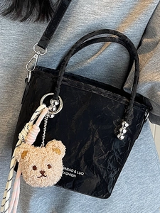 Sac seau noir tendance avec pendentif ours en peluche et sangle tissée sur modèle