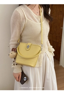 Macro detail of yellow leather bucket bag with silver twist lock and bear charm