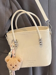 Sac seau minimaliste blanc crème avec doubles poignées et breloque ours sur modèle
