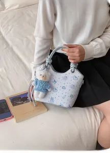 Detail of light blue floral bucket bag with a cute white teddy bear plush charm