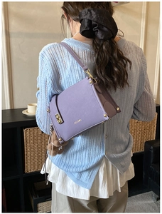 Détail du sac carré violet avec fermoir doré et breloque ours porté par un mannequin