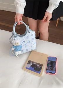 Detailed view of light blue printed bucket bag with cute bear charm and knot handle detail