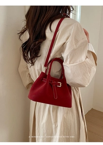 Rear view of a model wearing a minimalist red retro bucket bag with decorative buckle