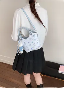 Detail of light blue bucket bag with cartoon bear print and plush bear keychain