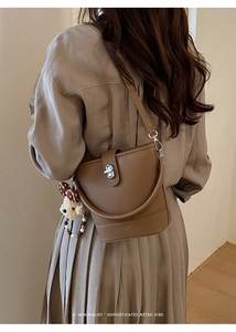 Detail of brown litchi pattern bucket bag with silver twist lock and bear charm