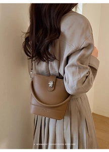 Close-up of a brown litchi pattern bucket bag with a silver twist lock and retro leather strap
