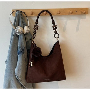 Detail of coffee suede Hobo bag featuring unique wooden bead strap and pompom charm