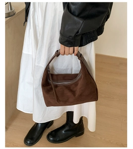 Deep brown matte suede hobo bag with silver zipper in a stylish urban outfit setting
