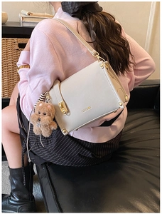 Vue de dessus d'un sac bandoulière beige rectangulaire avec fermoir doré et doudou ours