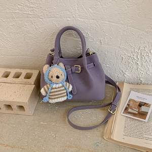 Detail of purple bucket bag with lychee texture, cute bear pendant and adjustable strap