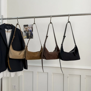 Collection of hobo shoulder bags in beige, brown, and black hanging on a metal rack