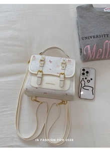 Detail of white mini backpack with pink bear prints and golden metal buckles on cloth