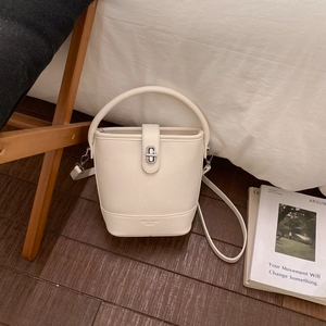 Close-up of white lychee-patterned leather bucket bag with silver metal swivel lock detail